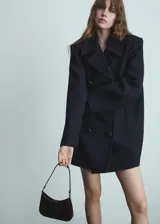 Abrigo de doble botonadura color negro, con corte oversized y diseño amplio.
