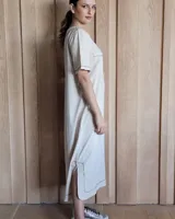 Vestido midi negro con cuello redondo y mangas cortas. Presenta dos bolsillos cuadrados en el pecho y ribetes blancos en cuello, mangas, bolsillos y ruedo.