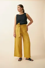 Pantalón palazzo color mostaza de tiro alto, con lazo ancho para atar en la cintura.