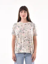 Remera blanca con estampado de flores y hojas en tonos pastel.