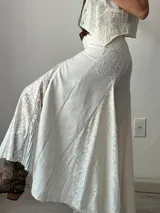 Pantalón blanco de corte palazzo con aplicaciones de encaje floral en los laterales.