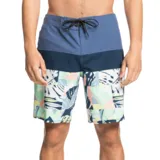 Boardshort de hombre con diseño de bloques de color y estampado tropical. La parte superior es azul claro, seguida de una franja azul marino, y la parte inferior presenta un estampado geométrico con hojas en tonos pastel y azul oscuro sobre fondo blanco. Posee cordón de ajuste negro en la cintura.