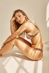 Conjunto de bikini blanco con textura, compuesto por un corpiño de triángulo fijo con breteles regulables y almohadillas desmontables, y una bombacha vedetina con frunce elástico en los costados.