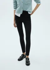 Pantalón negro ajustado al cuerpo, de tiro alto y largo tobillero.
