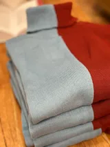 Polera de cuello alto, de punto acanalado, con diseño color block en celeste y bordó.