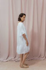 Vestido corto color beige de lino, con escote redondeado con lazo y mangas cortas amplias.