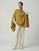 Poncho tejido de punto grueso, color mostaza/mostaza oscuro, con cuello redondo y caída amplia.