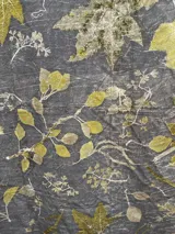 Mantel rectangular de algodón color gris con estampado de hojas y flores en tonos amarillos y marrones.