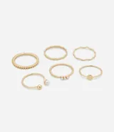 Set de seis anillos dorados de metal reciclado con diferentes diseños: texturizado, liso, con tres perlas pequeñas, con una perla y una esfera, y con una placa circular.