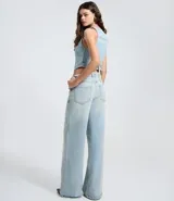 Pantalón de jeans azul de corte wide leg, tiro medio, con cintura de diseño traspasado y cierre tradicional.
