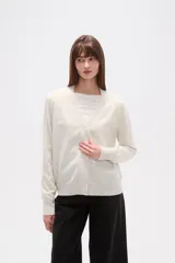 Cardigan de punto color blanco roto con motas oscuras, de manga larga y escote en V con cierre de botones frontales.