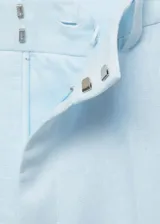 Pantalón de vestir celeste claro de lino, con tiro alto, corte recto, bolsillos laterales y traseros, trabillas y cierre frontal oculto con botón, gancho y cremallera.