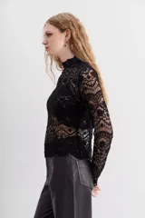 Camisa de tul negro con bordados, manga larga y cuello alto, con apertura en la espalda y escote gota.