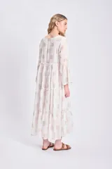 Vestido corto blanco con estampado de paneles geométricos dorados, escote en V con lazo ajustable y mangas largas acampanadas.