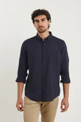 Camisa azul marino de lino y algodón, con cuello abotonado, manga larga con puños enrollados, bolsillo de parche en el pecho y cierre frontal con botones.