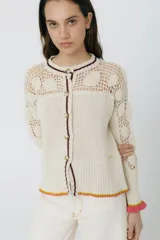 Cárdigan azul con detalles en crochet, mangas con volado y vivos de color rojo en cuello, puños y frente. Tiene botones al frente.
