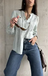 Camisa celeste con bordado inglés, cuello mao y mangas largas abullonadas con puños elásticos.