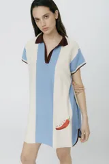 Vestido corto tipo polo, tejido en jersey liviano de algodón y acrílico, con rayas verticales en blanco y celeste, cuello marrón y bordado de un ají en el frente.