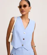 Chaleco celeste slim confeccionado en crepé, con escote en V y abotonado frontal con botones dorados.