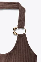 Top negro de tejido rib con escote asimétrico, manga sisa y tirante ancho con detalle de aro metálico dorado.