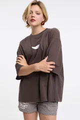 Remera marrón holgada con manga corta y estampado pequeño en el pecho. Ideal para usar con shorts o calzas.