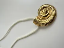 Collar con dije dorado en forma de concha de nautilus y cordón blanco.