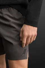Shorts deportivos color gris oscuro confeccionados en tejido técnico ligero y elástico con forro interior, cintura elástica ajustable con cordón, bolsillos laterales, bolsillo de seguridad en espalda con cierre de cremallera, bajo con aberturas laterales y detalle de logo estampado en pernera.