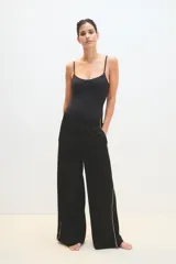 Pantalón palazzo negro con cintura elástica y una fina línea blanca vertical en los laterales.