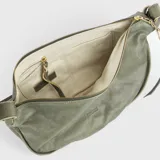 Bolso tipo bandolera de cuero color verde oliva, con textura suave y acabado desgastado. Presenta un diseño curvado y amplio, con correa ajustable sujeta con hebillas y pasadores de cuero de color más claro. El interior está forrado y cuenta con tres bolsillos.