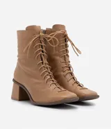 Bota de cuero color marrón claro, de caña media, con puntera cuadrada, taco bloque y cierre con cordones y cremallera.