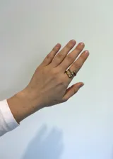 Anillo dorado de acero inoxidable con forma de nudo abierto.