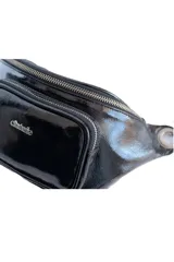 Riñonera negra de charol con correa ajustable y cierre plateado.