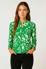 Camisa verde con estampado de hojas y flores blancas, cuello mao y cierre frontal con botones.