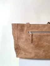 Cartera tipo tote de cuero graneado color negro, con textura uniforme y suave al tacto. Tiene manijas de 55 cm, bolsillo frontal con broche imantado, bolsillo trasero con cierre metálico, cierre principal metálico, forro interior y tres bolsillos internos (uno con cierre, uno plaqué y uno tipo sobre con solapa y botón).