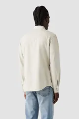 Camisa de manga larga color beige, con cierre de botones a presión, dos bolsillos frontales con solapa y logo de la marca en etiqueta roja en el bolsillo izquierdo.