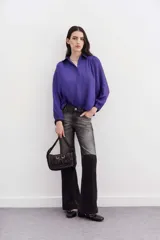 Camisa blanca de manga larga confeccionada en viscosa con acabado sandwash, de textura suave y aterciopelada. Cuello camisero con botón en forma de corazón y frunces en el canesú delantero y la espalda.