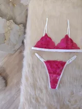 Conjunto de lencería fucsia de encaje floral, compuesto por un corpiño triangular sin aro y una tanga con tiras finas blancas.