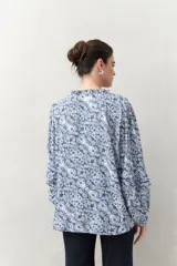 Camisa de manga larga estampada en azul y blanco, confeccionada en viscosa, con cuello mao con pequeño volado y mangas con leve volumen.