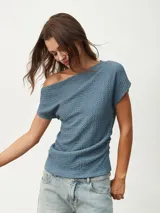 Remera azul piedra con textura, de escote asimétrico y manga corta.