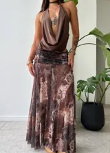 Pollera larga de tela liviana y traslúcida con estampado abstracto en tonos marrones, negros y rosados. Presenta frunces en la cintura y corte al tobillo.