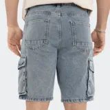 Bermuda de jean celeste lavado, estilo cargo, con bolsillos laterales con fuelle y cierre de botón y cremallera.