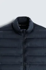Cazadora acolchada negra de tejido técnico, con cuello subido, manga larga, bolsillos de vivo en la cadera, acabados con elástico y cierre frontal de cremallera.