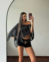 Poncho negro de mangas largas con detalle de transparencia en los hombros.