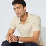 Chomba de piqué de algodón color beige con cuello clásico y tapeta de dos botones.