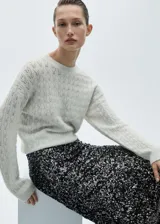 Sweater de punto grueso color crudo con detalle de lúrex, cuello redondo y manga larga.