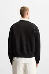 Cárdigan negro de punto de algodón, corte relaxed fit, con cuello en V, manga larga, terminaciones en rib y cierre frontal con botones.
