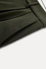 Bermuda larga color verde oscuro de tiro medio y pierna ancha. Confeccionada en hilatura con 19% de lana. Presenta trabillas en la cintura, bolsillos laterales y con solapa en la espalda, pinzas en el delantero y cierre frontal con cremallera y botones.