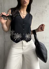 Chaleco negro de lino con bordado de palmeras en el ruedo, escote en V y cierre frontal con botones.