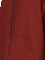 Buzo rojo con cuello alto, cierre de cremallera, dos bolsillos delanteros tipo canguro y logo de Tommy Hilfiger bordado en el pecho.