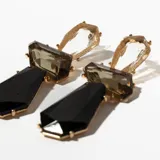 Aros colgantes con piezas geométricas de cristal transparente, marrón y negro, con engarce dorado.